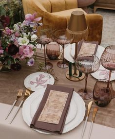 the table is set with wine glasses and place settings