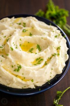 mashed potatoes with parsley in a blue bowl on a wooden table, ready to be eaten