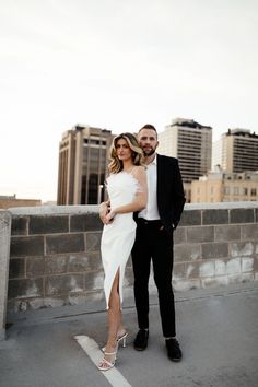 a man and woman in formal wear posing for a photo on the roof of a building