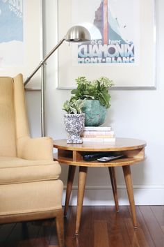 a living room with a table and chair next to a lamp on top of a hard wood floor