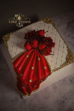 a cake that is decorated with red flowers and gold trimmings on the top