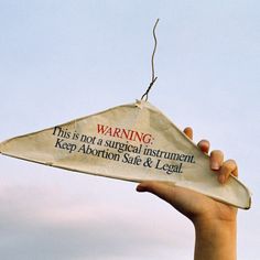 a kite flying in the sky with someone's hand holding it up and saying warning