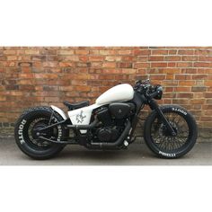 a white and black motorcycle parked in front of a brick wall