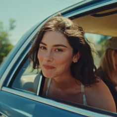 a woman sitting in the back seat of a car with her head out the window