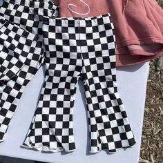 Rock some fun and cute style with these Checkered Bellbottom Ruffled Toddler Pants! Your little cutie will be the coolest kid on the block in these super cute pants that feature a playful checkered pattern and fun ruffled bottoms. Perfect for making a statement and keeping your child comfortable and stylish. Casual Ruffled Bottoms For Playtime, Trendy Bottoms For Spring Playtime, Trendy Spring Bottoms For Playtime, Cute Ruffled Bottoms For Playtime, Cute Plaid Bottoms For Spring, Cute Plaid Spring Bottoms, Spring Playful Gingham Bottoms, Toddler Pants, Cute Pants