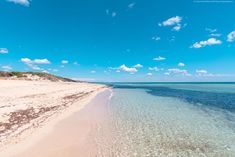 an empty beach with clear water and blue skies