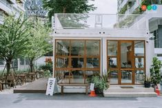 the outside of a building with tables and chairs on it's sides, surrounded by trees