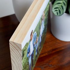 a wooden photo frame sitting on top of a table next to a potted plant