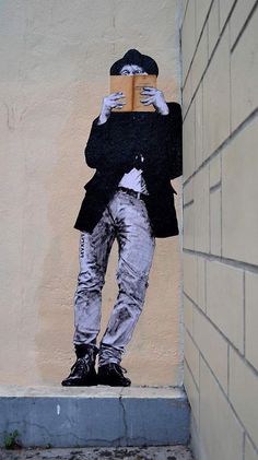 a man with a book in his hands is painted on the side of a building