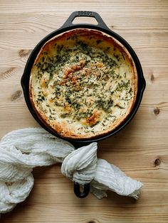 a skillet filled with food sitting on top of a wooden table next to ropes