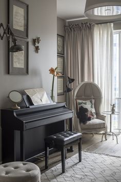 a living room with a piano, chair and ottoman in front of a large window