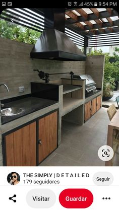 an outdoor kitchen with wood cabinets and stainless steel appliances on the counter top, under a pergolated roof