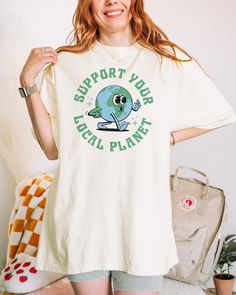 Support Your Local Planet t-shirt. These tees are Comfort Colors and are made to last using premium ringspun cotton, this creates an vintage-soft shirt. The soft-washed, garment-dyed fabric brings extra coziness to your wardrobe while the relaxed fit makes it an excellent daily choice. ✦ 100% Ringspun Cotton ✦ Color: Ivory, Pepper, Orchid ✦ Relaxed fit ✦ Medium fabric ✦ Sewn-in twill label ✦ Eco-friendly, Ethically Made & Sweatshop Free ✦ Printed to order with non-toxic ink ✦ Durable and Long-lasting ✦ Shirts are pre-shrunk but may shrink slightly after washing ✦ Made to order: *Please allow 2-5 business days to print before being shipped* Sizing Recommendation: ✦ See size guide in images above ✦ This is a unisex t-shirt. Order your usual size for a relaxed fit, size down by one if you pre Support Your Local Planet, Earth Day Text Print Crew Neck Top, Earth Day Graphic Tee With Crew Neck, Planet Earth Day, Casual Earth Day Screen Print T-shirt, White T-shirt With Earth Day Graphic Print, Casual Slogan T-shirt For Earth Day, Earth Day Shirt, The Planet Earth