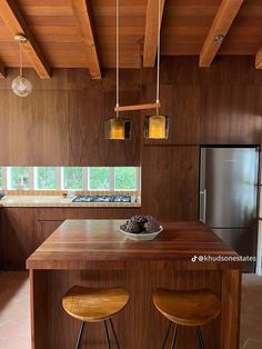 a kitchen with two stools next to an island in the middle of the room