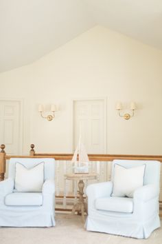 two white chairs sitting next to each other in a living room