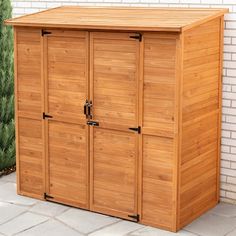 a large wooden storage shed sitting on top of a patio next to a brick wall