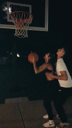 two people are playing basketball in the dark