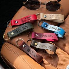 six leather keychains with personalized names and date on them, sitting on a car seat