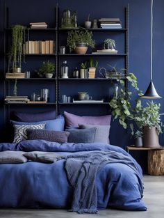 a bed with blue sheets and pillows in front of a bookshelf filled with plants