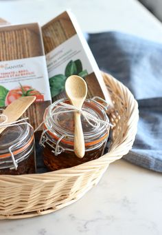 a basket filled with jams on top of a table next to a wooden spoon