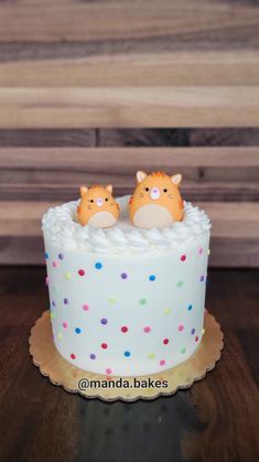 two cats sitting on top of a cake with sprinkles and polka dots