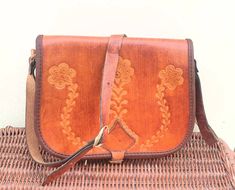 This is a beautiful messenger bag in thick golden brown leather with floral design impressed on to the front flap.  Full flap with buckle to close.  Inside in reverse leather with a central zipped dividing pocket.  Excellent condition no scuffing to the leather lining also clean and unmarked.  Looks to have had very minimal previous use (if at all). Size - width 9 inches  (23 cm)            depth  7.5 inches  (19 cm)            shoulder strap 42 inches ( 107 cm) Traditional Brown Satchel Saddle Bag, Brown Leather Messenger Bag, Cross Body Satchel, Black Leather Top, Boho Hippie Chic, Hobo Purse, Leather Messenger Bag, Satchel Purse, Saddle Bag