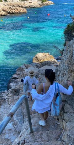 two people walking up some steps near the water