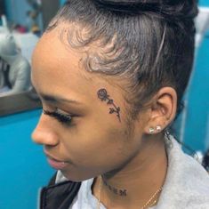 a woman with a flower tattoo on her forehead and behind her ear is looking at the camera