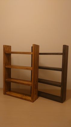 two wooden bookshelves sitting next to each other on top of a brown floor