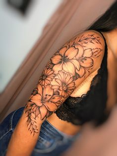 a woman's half sleeve with flowers on her left arm and the back of her shoulder