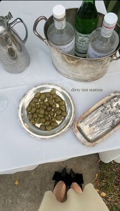 a table topped with metal pans filled with olives next to bottles of water