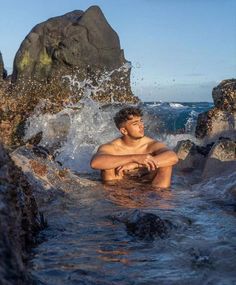 a man sitting on rocks in the ocean