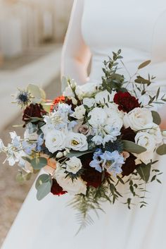 a bridal holding a bouquet of white and red flowers