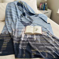 an open book laying on top of a bed under a blue blanket with words all over it