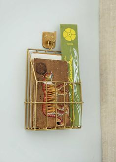 a gold metal holder with books on it and a green box in the corner next to it