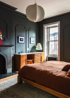 a bedroom with a bed, dresser and fireplace in the corner next to a window