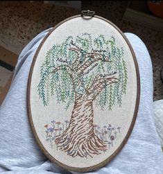 a person is holding up a cross stitch tree