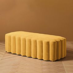 a yellow bench sitting on top of a hard wood floor next to a brown wall