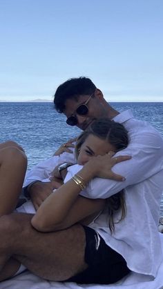 a man and woman sitting next to each other on a boat in the ocean with their arms around each other