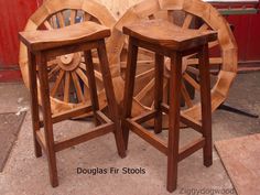 two wooden stools sitting next to each other in front of a red building with wheels on it