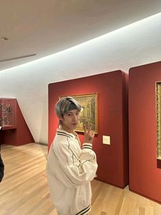 a man standing next to a painting in a room filled with red and white walls