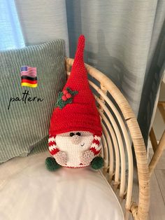 a knitted gnome sitting on top of a bed next to a pillow