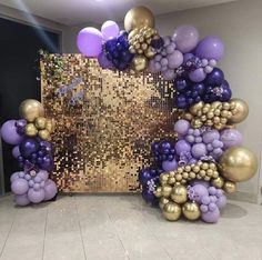 a large balloon arch with purple and gold balloons