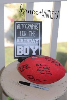 a football sitting on top of a wooden table next to a sign that says autographs for the birthday boy