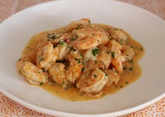 a white plate topped with shrimp and gravy on top of a orange table cloth