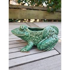 a ceramic frog planter sitting on top of a wooden deck