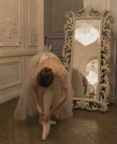 a ballerina is bending over in front of a mirror