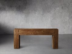 a small wooden table sitting on top of a cement floor next to a gray wall