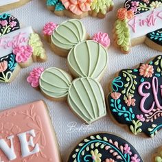 decorated cookies are arranged on a table with name plates and cookie cutters in the shape of cacti