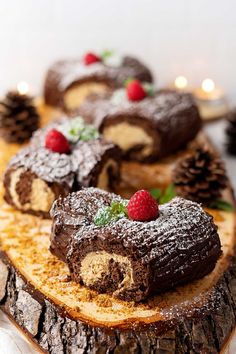 mini mocha yule logs with raspberries on top and pine cones in the background